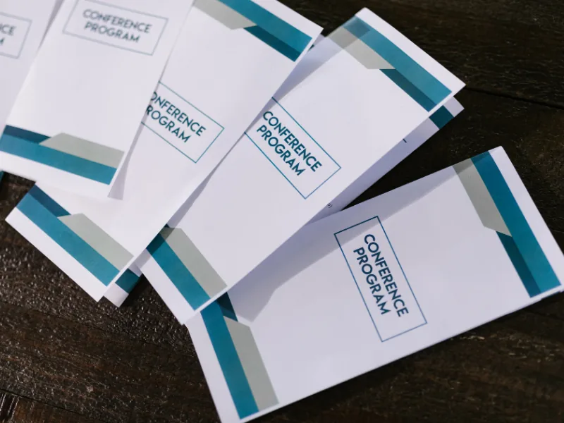 Folders de programação de evento impressos e organizados sobre a mesa